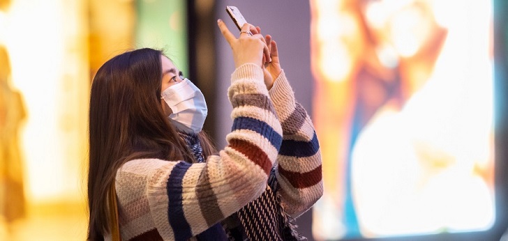 Mujer con mascarilla en China Banco de España: el PIB puede caer hasta un 13,6% si se alarga el confinamiento